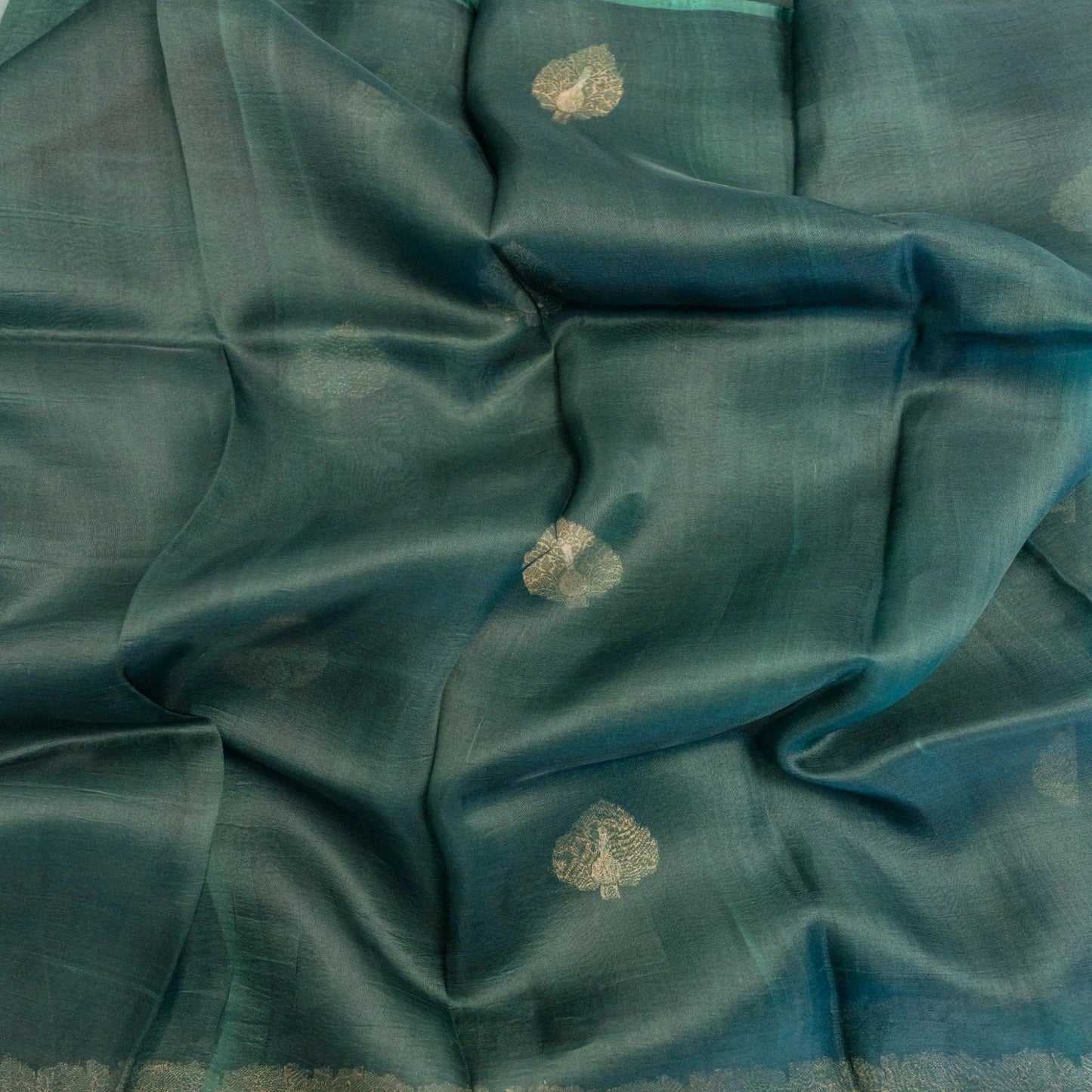 Teal fabric with gold floral patterns, possibly a sari or fabric swatch.