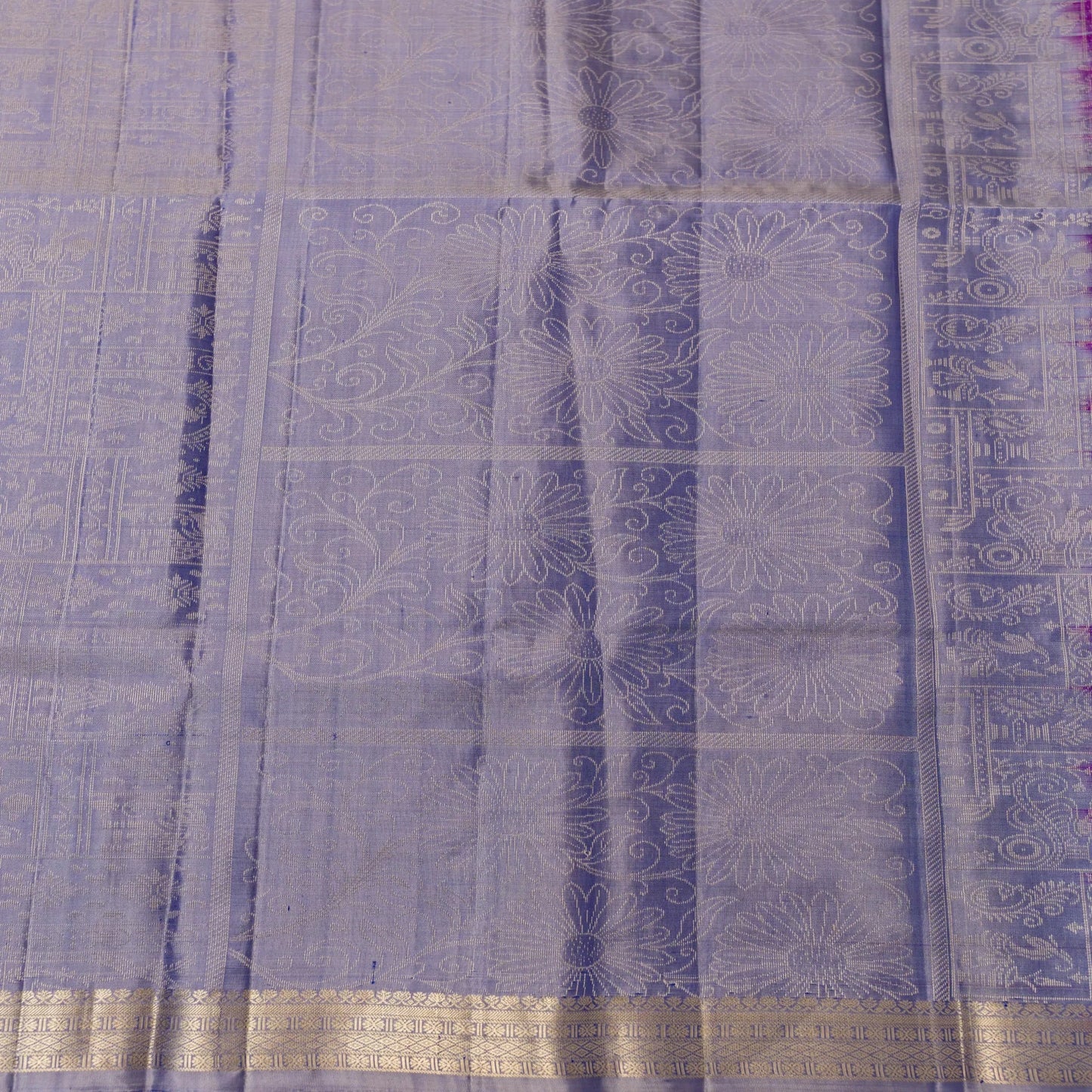 Close-up of a purple fabric with intricate patterns and a gold border.