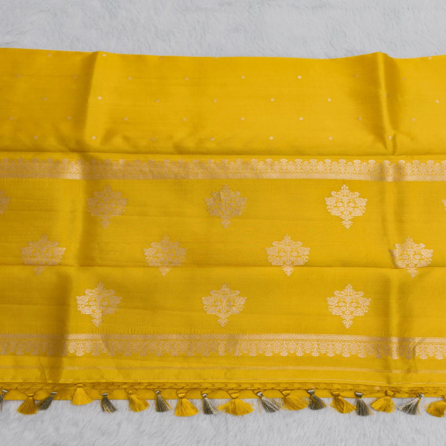 Yellow fabric with gold patterns and tassels on a white background