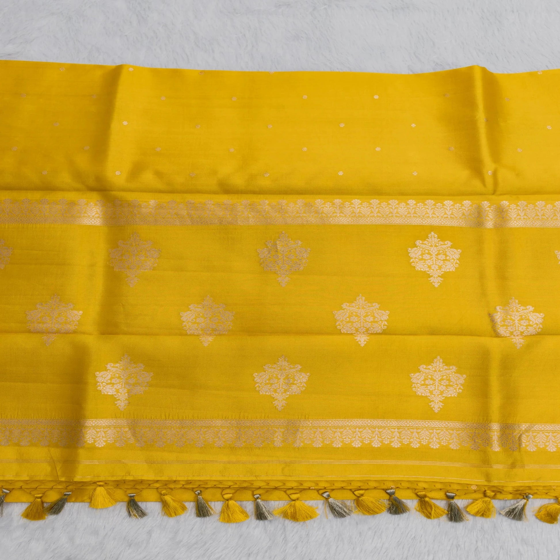 Yellow fabric with gold patterns and tassels on a white background