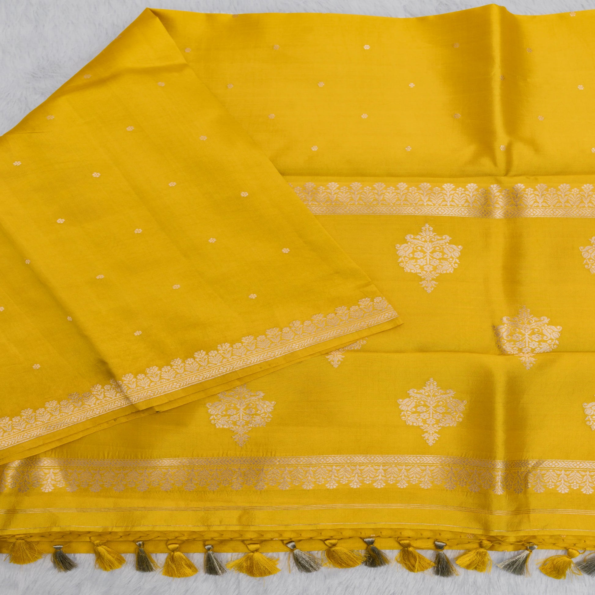 Yellow saree with gold border and tassels on a white background