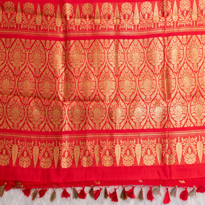 Red fabric with gold intricate patterns and tassels on a white background