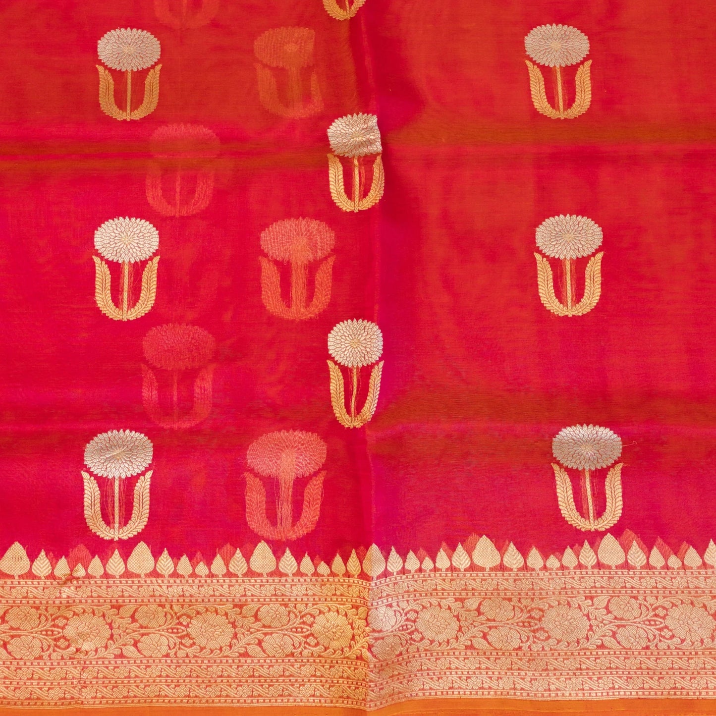 Red fabric with gold floral patterns on a plain background