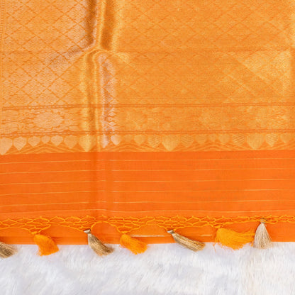 Close-up of an orange fabric with intricate patterns and tassels on a white background