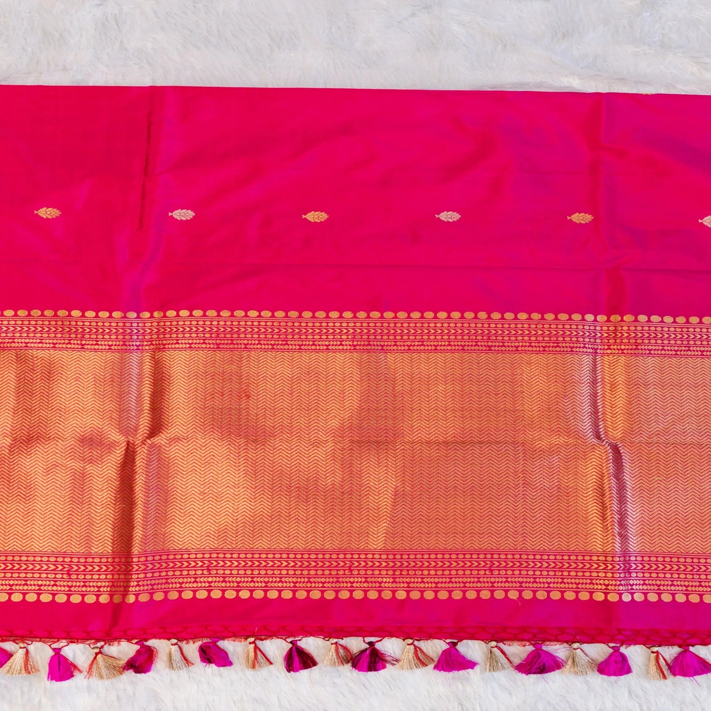 Pink and orange saree with decorative border on a light gray background