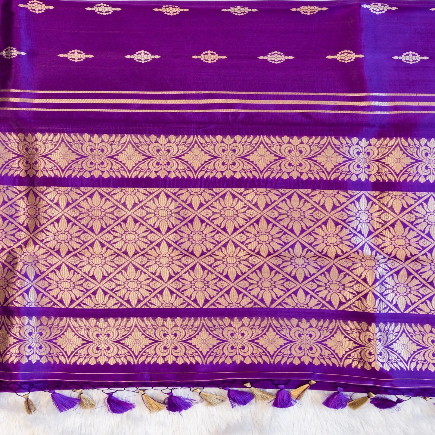Purple fabric with gold patterns and tassels on a white background