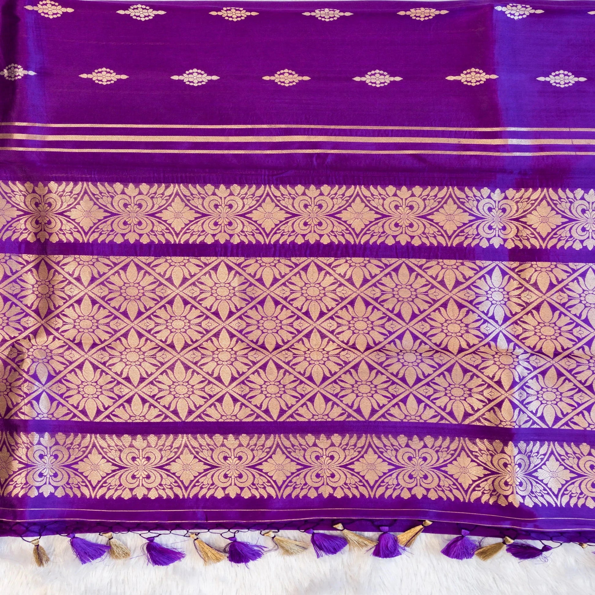 Purple fabric with gold patterns and tassels on a white background