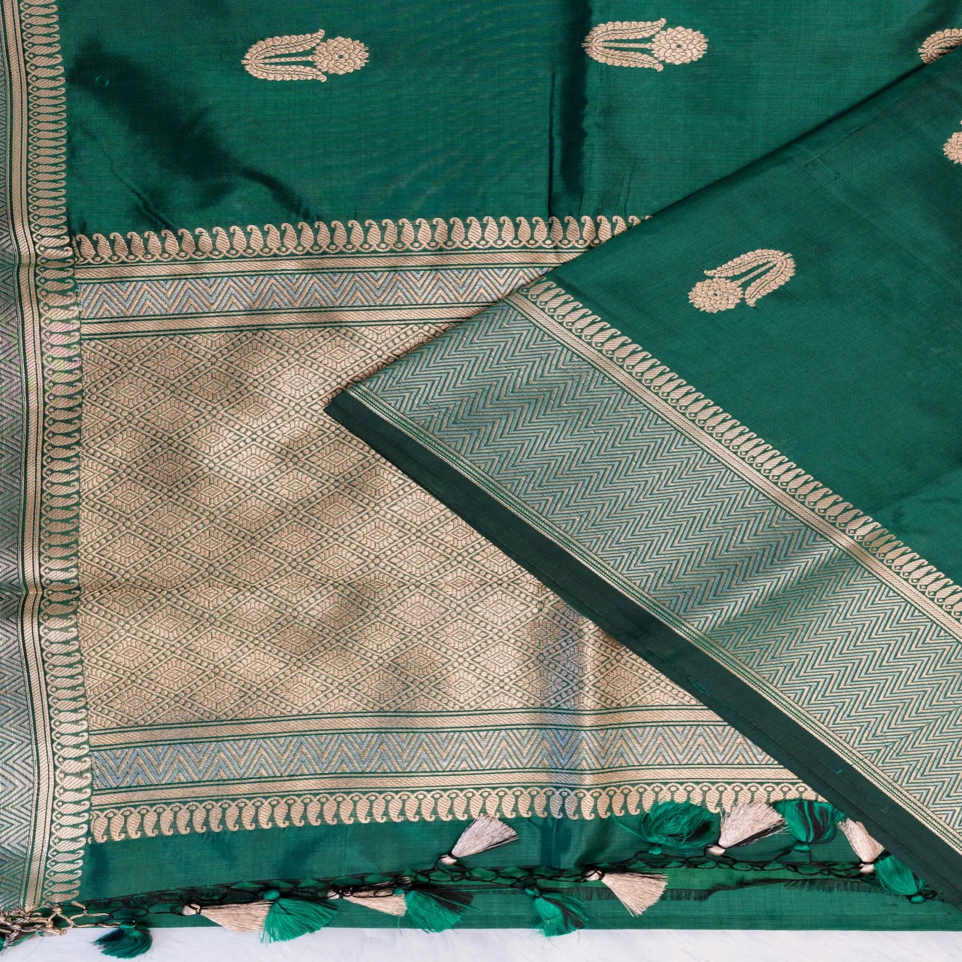 Green saree with gold patterns and border on a white background