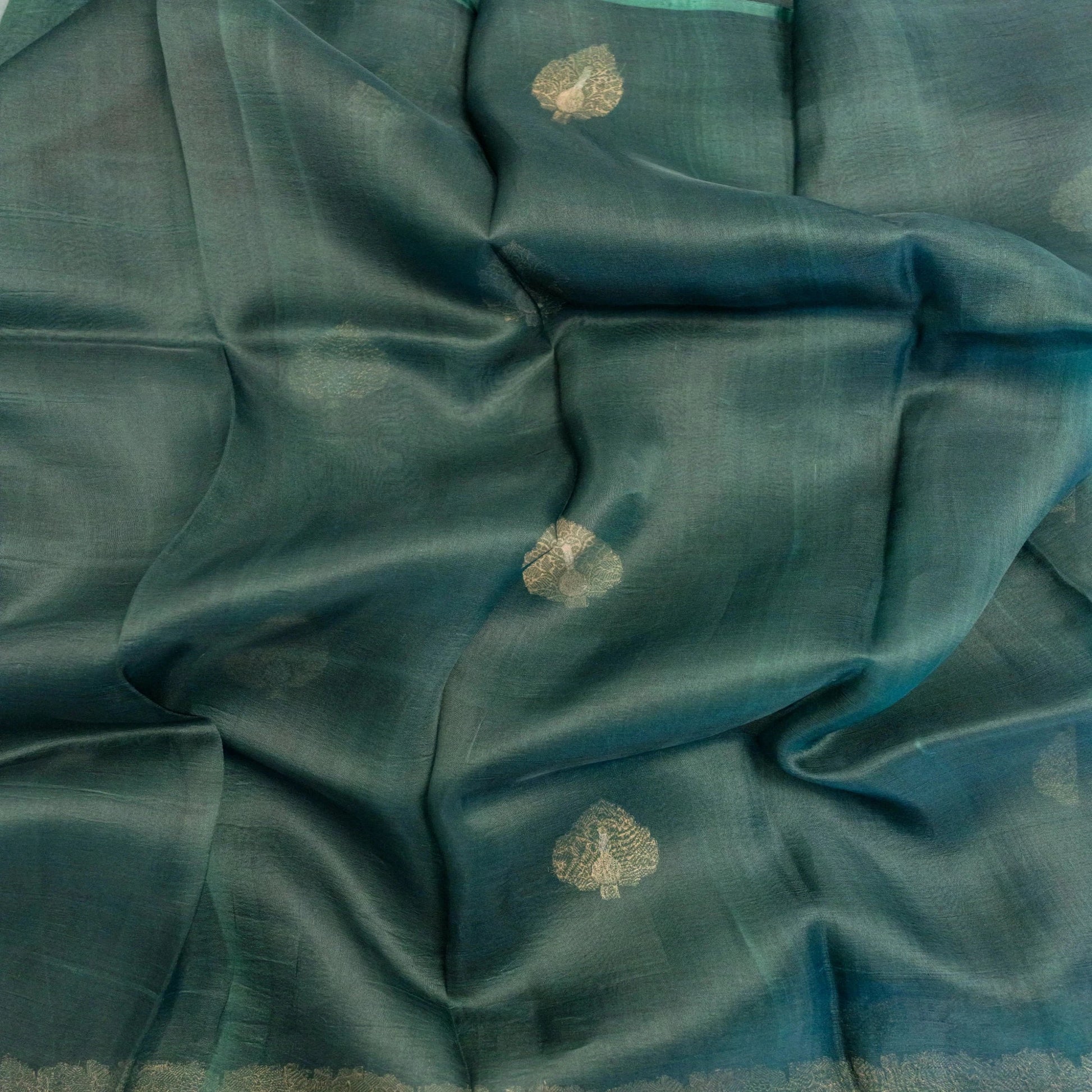 Teal fabric with gold floral patterns, possibly a sari or fabric swatch.