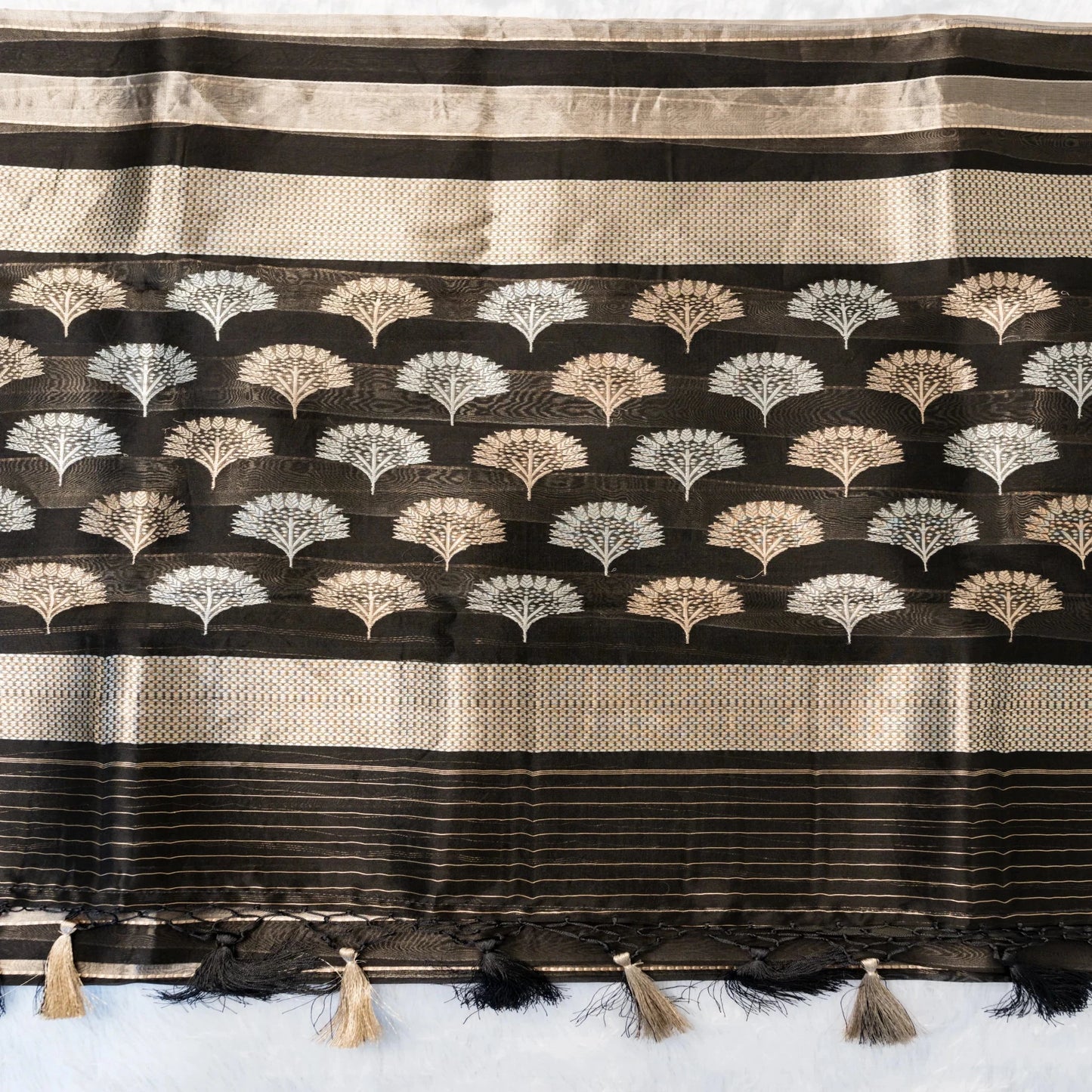 Black and beige striped fabric with decorative patterns and tassels on a white background