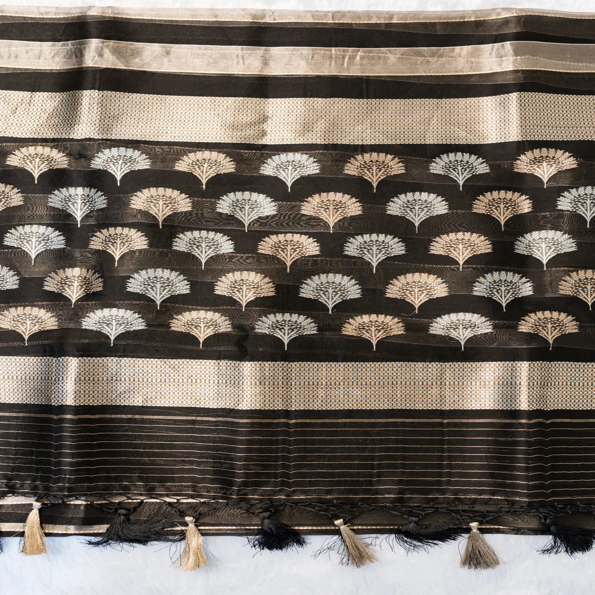 Black and beige striped fabric with decorative patterns and tassels on a white background