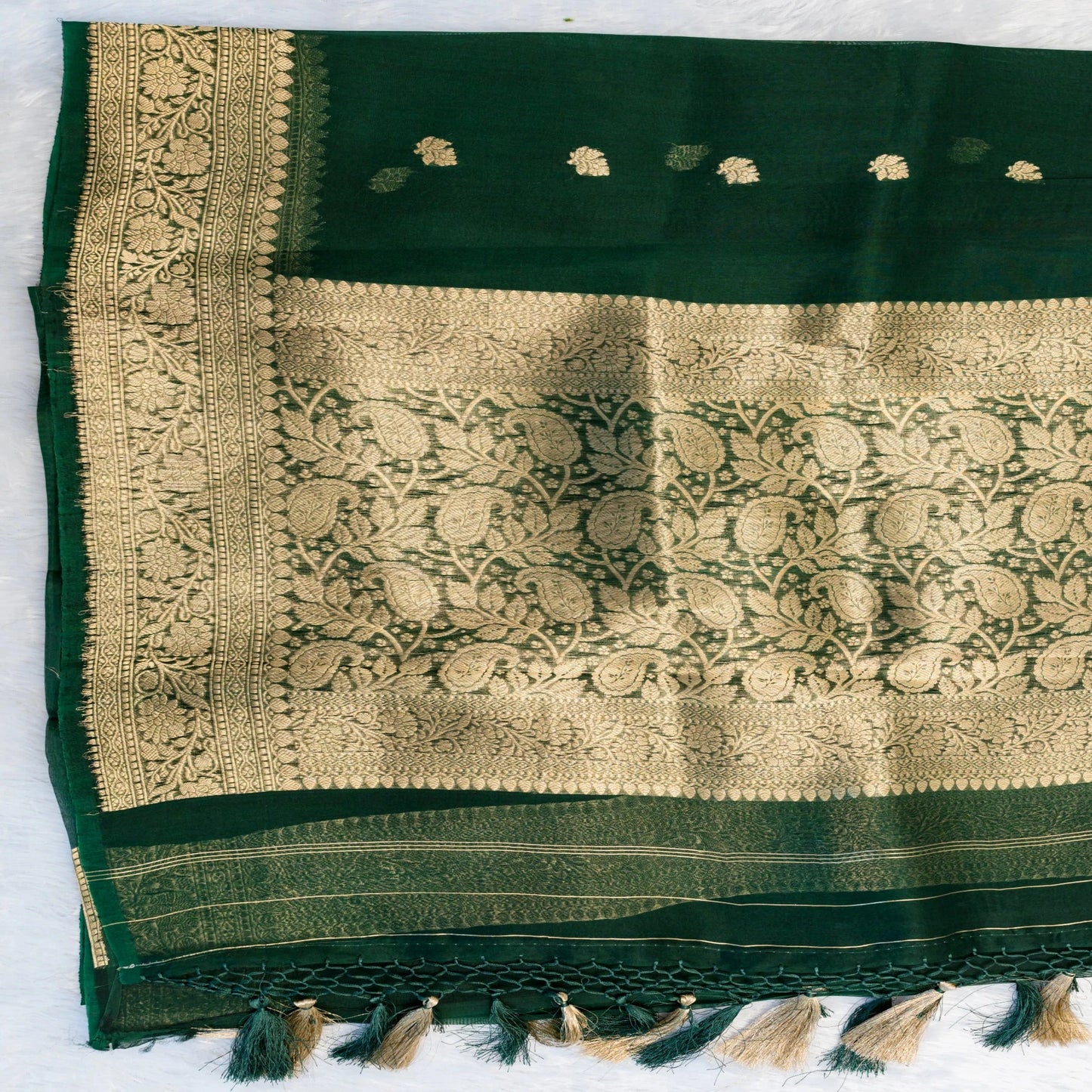 Green fabric with gold embroidery and tassels on a white background