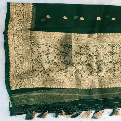 Green fabric with gold embroidery and tassels on a white background