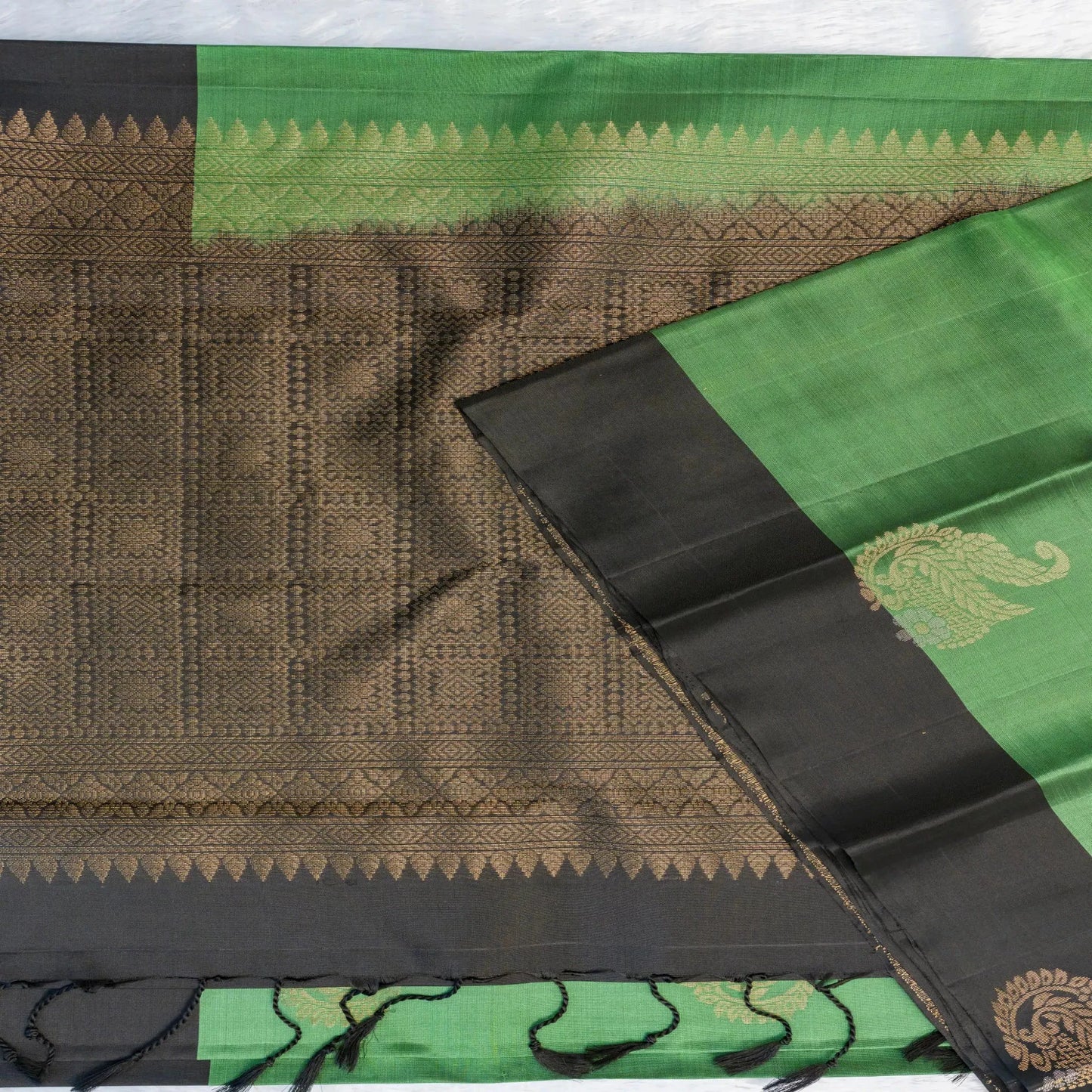 Traditional saree with green, black, and brown patterns on a white background