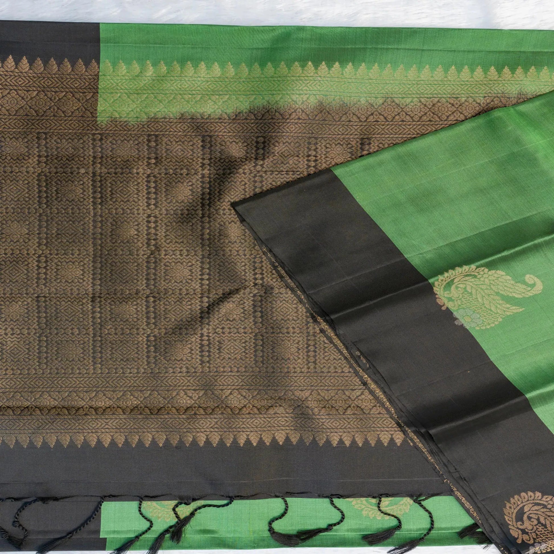 Traditional saree with green, black, and brown patterns on a white background