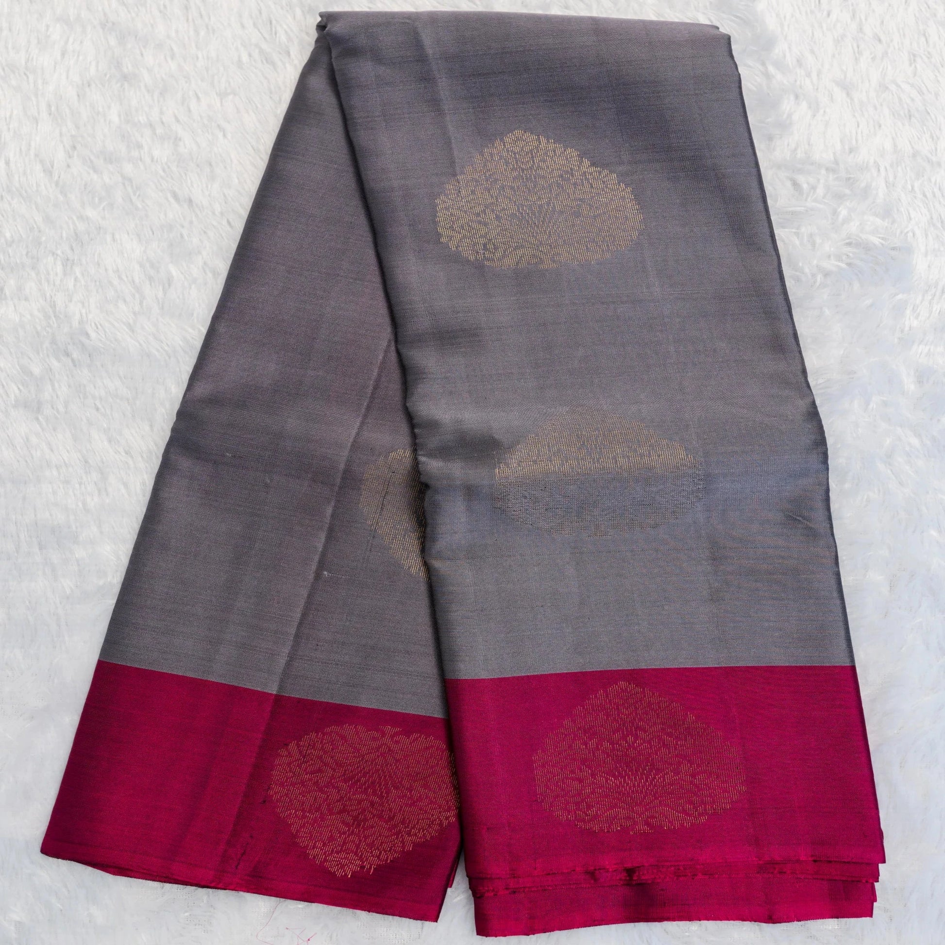 Gray saree with red border and gold floral patterns on a textured white background