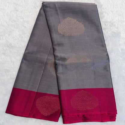 Gray saree with red border and gold floral patterns on a textured white background