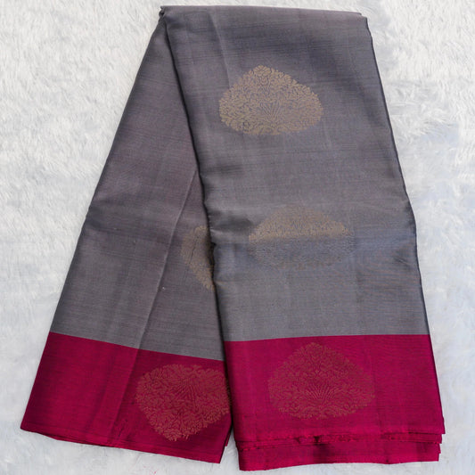 Gray saree with red border and gold floral patterns on a textured white background