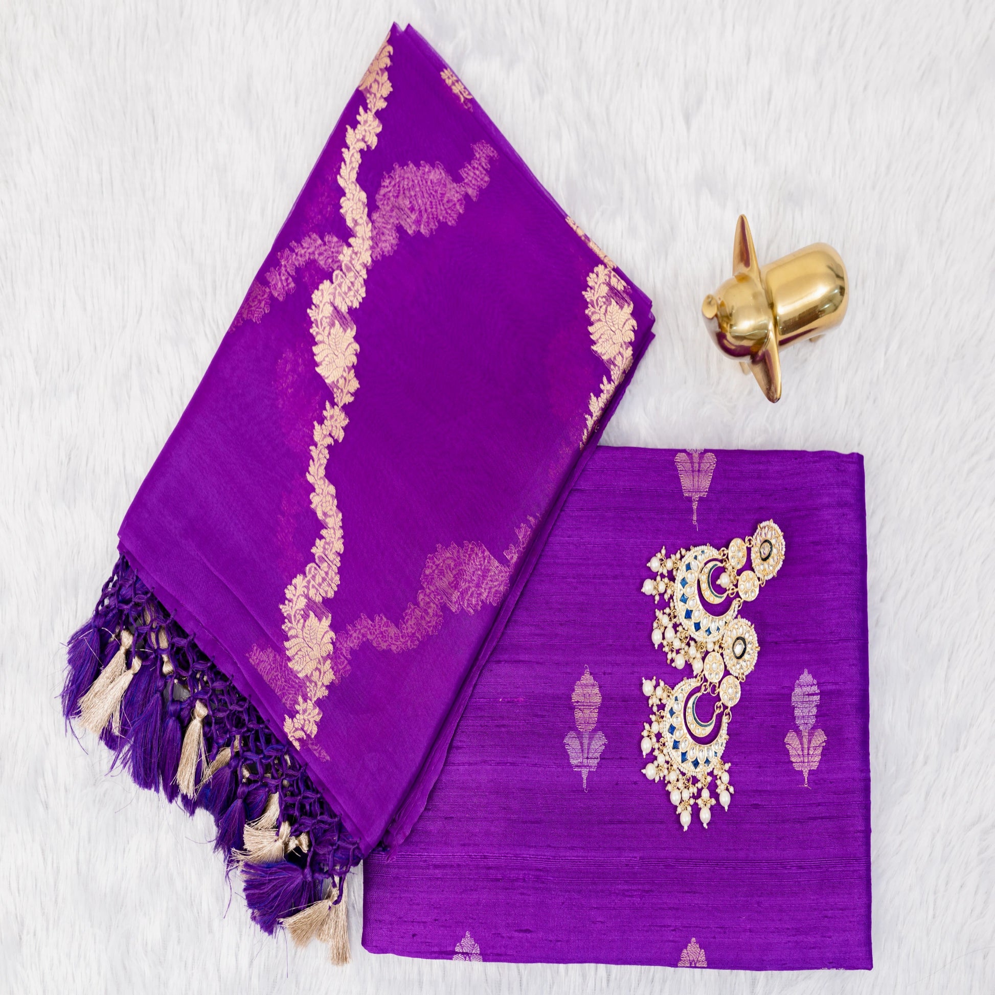 Purple fabric with gold embroidery and tassels on a white background