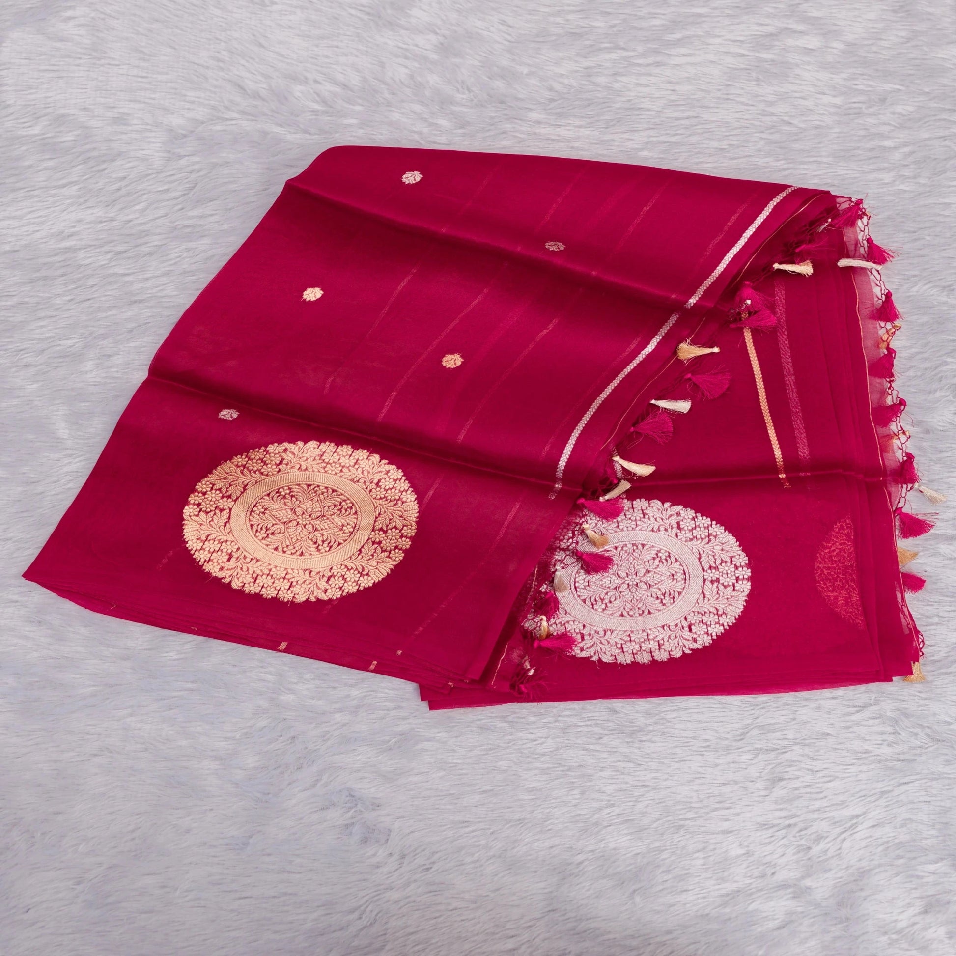 Red saree with gold embroidery on a light gray background