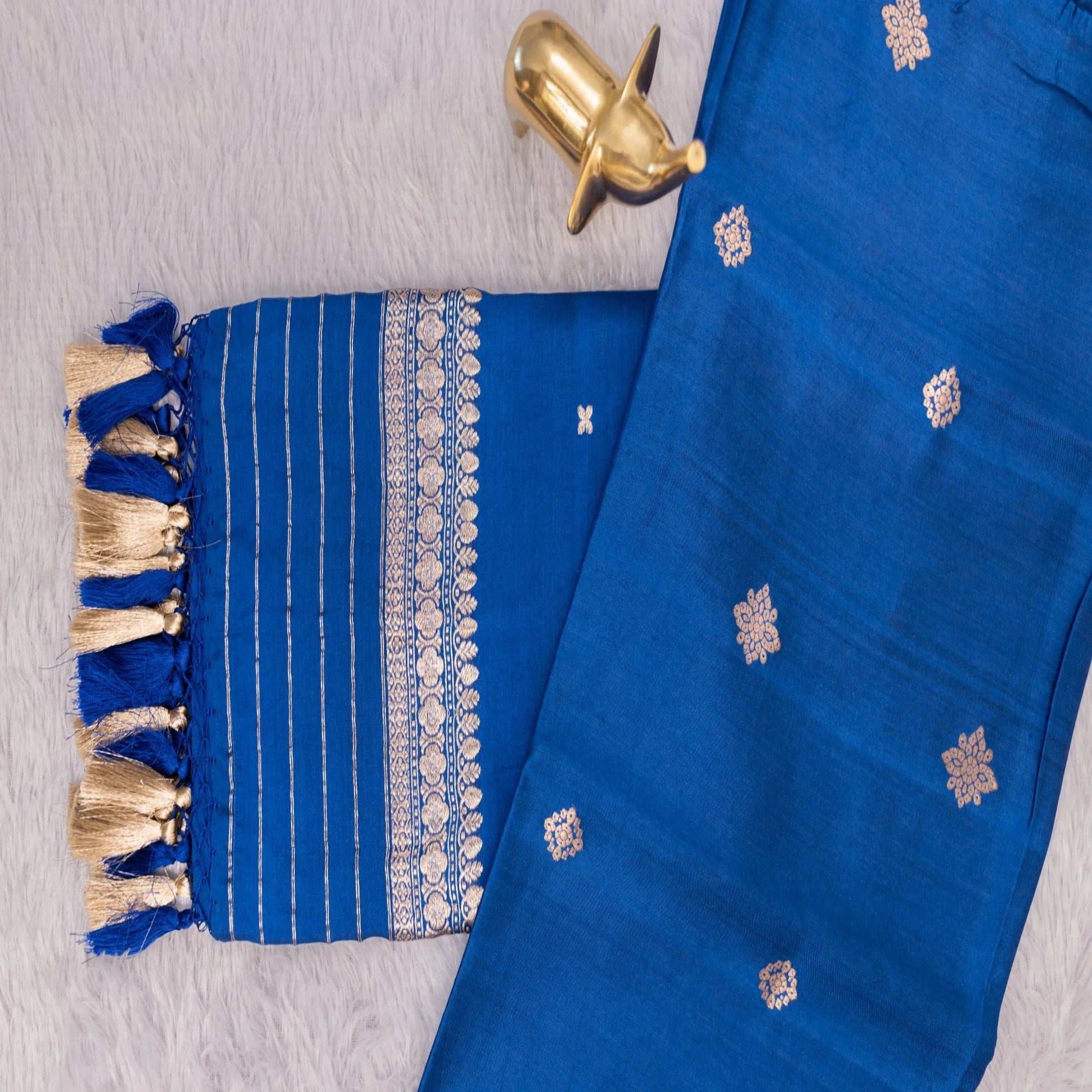 Blue fabric with gold embroidery and tassels on a textured surface